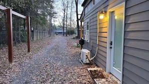 A pathway leading to a house with a covered porch and a door with a light fixture.