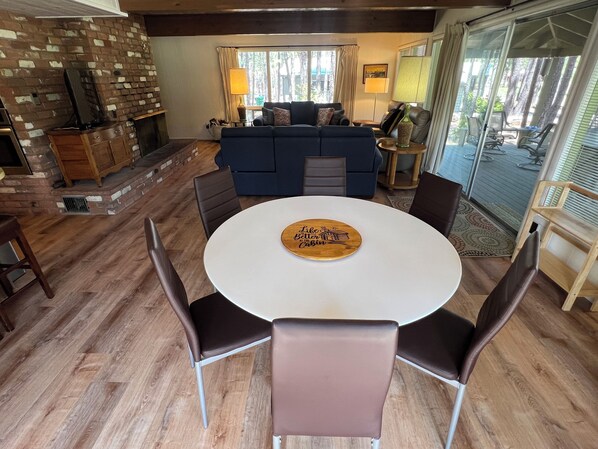 Uma sala de estar acolhedora com lareira, um sofá azul e uma mesa de jantar com cadeiras.