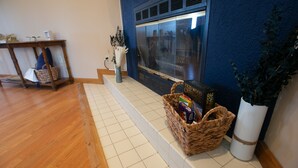 Une pièce avec une cheminée, une table en bois, un panier en osier et une plante en pot.