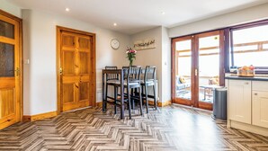 Un comedor con suelo de espiga, puertas de madera y vistas a través de un ventanal.