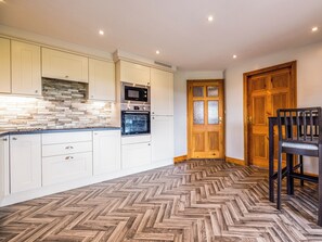 A kitchen with white cabinets, a herringbone wood floor, a microwave, and an oven.