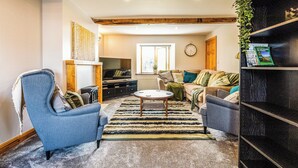 Una sala de estar acogedora con un sofá, sillones, una mesa de centro y una estantería.