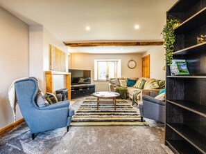 A cozy living room with a blue armchair, a sofa, a coffee table, and a bookshelf. - 2 bedroom accommodation in Cowan Bridge, near Kirkby Lonsdale (Cowan Bridge, near Kirkby Lonsdale)