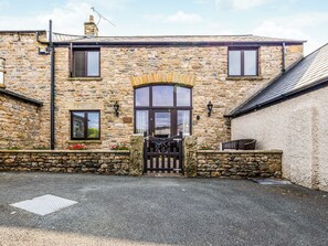 A stone building with a gated entrance, a large window, and a small door.