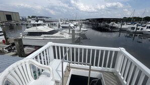 A marina with multiple boats docked, a white railing, and a view of the water.