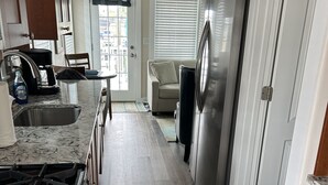 A modern kitchen with a gas stove, stainless steel refrigerator, and a dining area with a table and chairs.