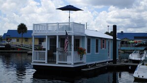 A houseboat with a porch, an American flag, and a dock.