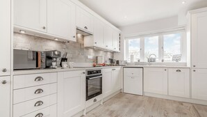 A modern kitchen with white cabinetry, a microwave, oven, and a window with a view.
