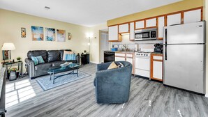 A modern kitchen with white cabinets, a stainless steel refrigerator, and a microwave.