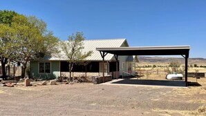 A rustic building with a covered porch, a stone foundation, and a clear view of the surrounding landscape.