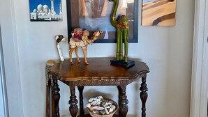 A wooden table with a vase and figurines, set against a wall with framed pictures.