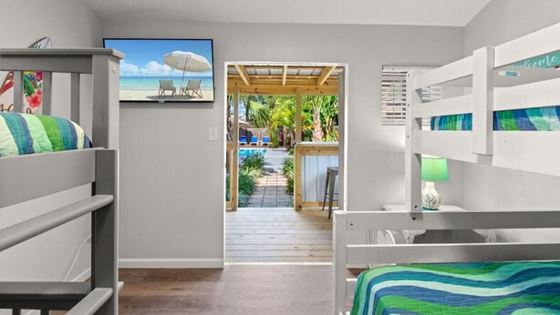 A bedroom with bunk beds, a TV, and a view of a pool area.