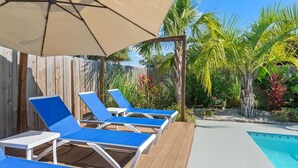 A poolside area with blue lounge chairs and a wooden deck.