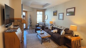A living room with a television, a coffee table, a sofa, a small Christmas tree, and a fireplace. - Tucker Mountain Lodge @ Copper Mountain (Copper Moutain)