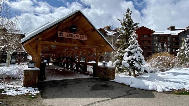 A wooden covered entrance to Center Village with a sign, snow-covered ground, and buildings in the background. - Tucker Mountain Lodge @ Copper Mountain (Copper Moutain)