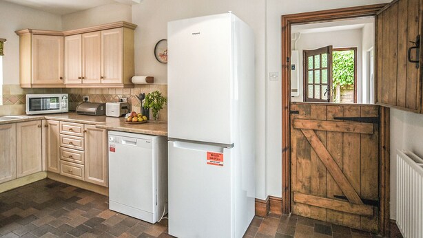 A kitchen with wooden cabinets, a white refrigerator, a microwave, and a toaster. - 6 bedroom accommodation in Dorrington, near Church Stretton (Dorrington, near Church Stretton)