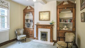 A traditional room with a fireplace, bookshelves, and two patterned chairs. - 6 bedroom accommodation in Dorrington, near Church Stretton (Dorrington, near Church Stretton)