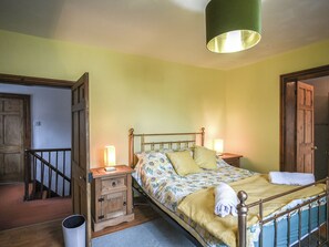A bedroom with a bed, bedside tables, a lamp, and a wooden door.