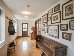 A hallway with wooden flooring, a bench, a coat rack, and a door. - 6 bedroom accommodation in Dorrington, near Church Stretton (Dorrington, near Church Stretton)