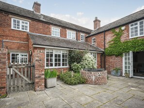 A brick house with a garden, a wooden gate, and a brick planter.