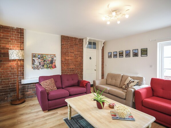 Olohuoneessa on kaksi sohvaa, sohvapöytä, lattiavalaisin ja ilmoitustaulu.