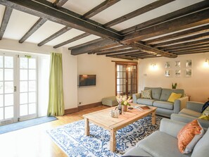 Una sala de estar con techo de madera, un sofá, una mesa de centro y un televisor.