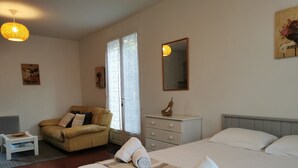 A bedroom with a bed, a sofa, a dresser, and a nightstand. - Studio Confort Cerise (Bayonne)
