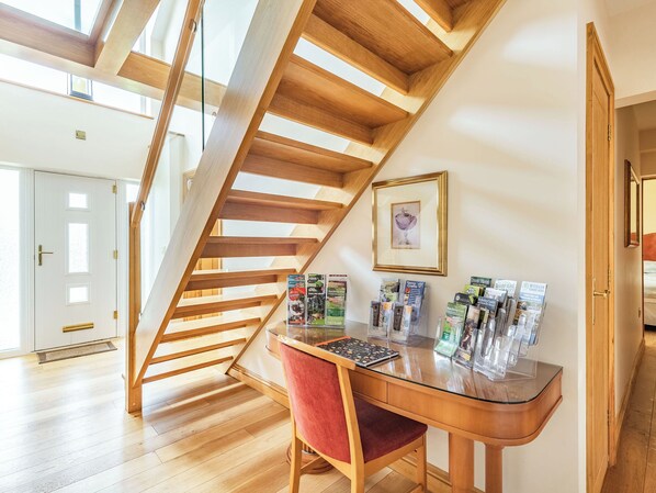 A wooden staircase, a desk with magazines, and a framed picture on the wall.