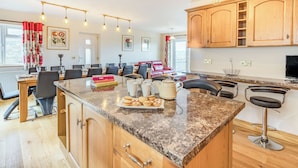 A modern kitchen with wooden cabinets, a granite countertop, and a dining area with a table and chairs.
