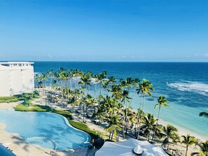Een resort met een groot zwembad, palmbomen en uitzicht op de oceaan.