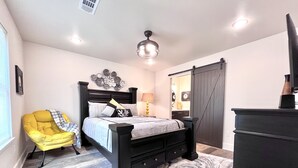 A bedroom with a bed, a yellow chair, a dresser, and a mirror. - Eagle's Nest - Beautiful House close to boat launch and local attractions.  (Russellville)