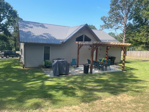 Uma casa com varanda coberta, churrasqueira e quintal cercado.