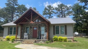 A house with a stone facade, a red door, and a welcoming sign. - Eagle's Nest - Beautiful House close to boat launch and local attractions.  (Russellville)