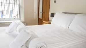 A neatly made bed with white linens and rolled towels. - 1 Greenswood Court (Brixham)