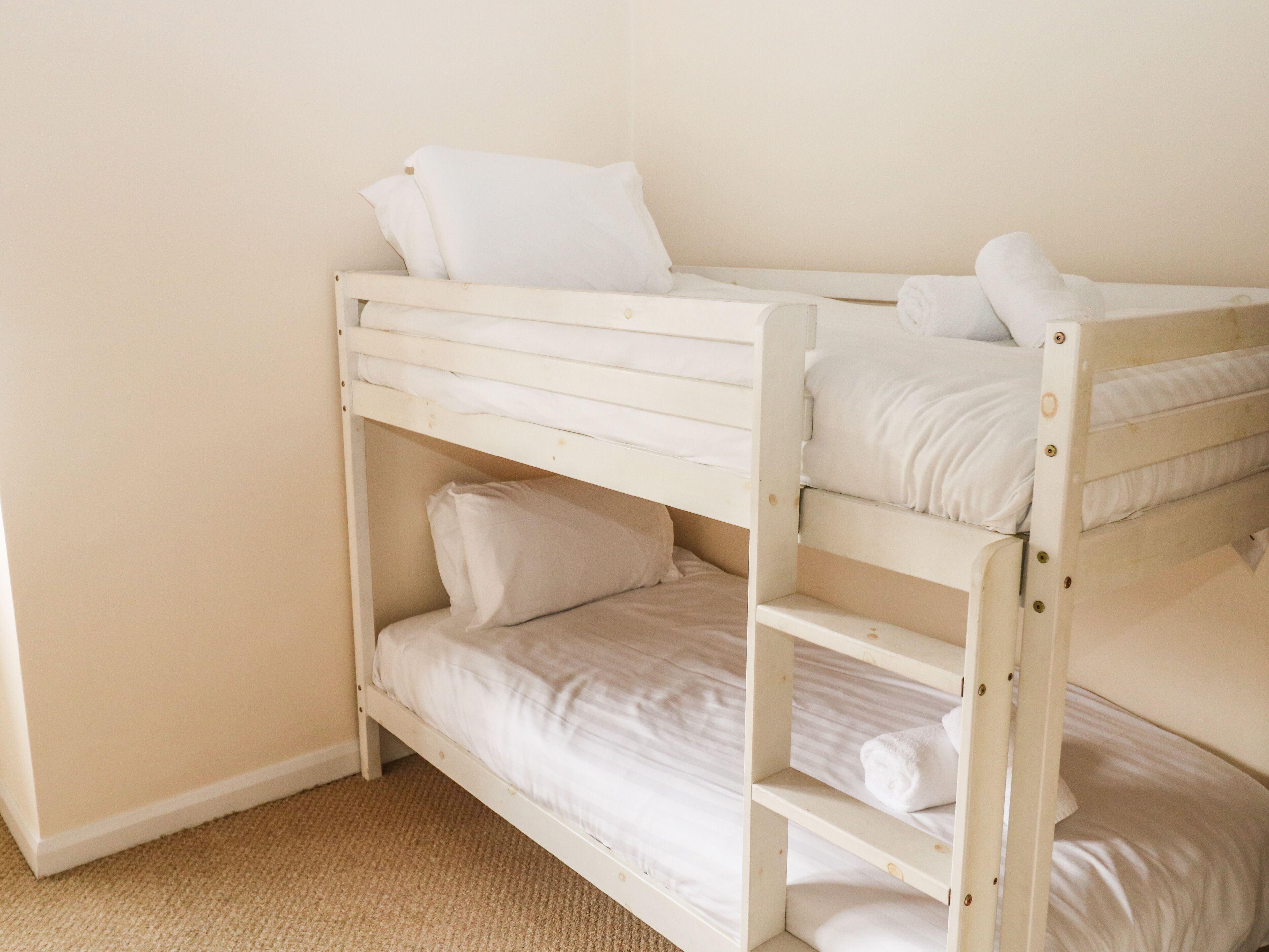 A bunk bed with white bedding and pillows.