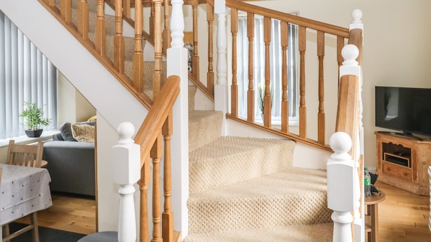 A staircase with wooden balusters and white spindles, leading to a landing area with a textured beige carpet. - 1 Greenswood Court (Brixham)