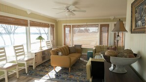 A living room with a sofa, chairs, a coffee table, a floor lamp, and a decorative bowl on a side table.