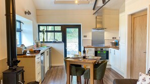 A modern kitchen with a dining area, a built-in stove, and a view through the door. - 1 bedroom accommodation in Stockton Brook, near Leek (Stockton Brook, near Leek)