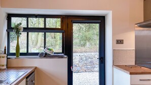 A kitchen with a stone wall, a wooden countertop, and a window with a view of trees. - 1 bedroom accommodation in Stockton Brook, near Leek (Stockton Brook, near Leek)