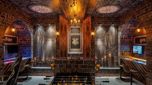 A room with a foosball table, brick walls, and a Harry Potter-themed sign.
