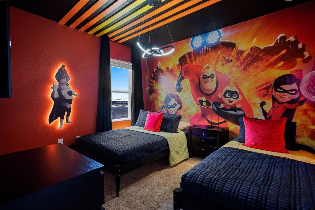 Quarto com duas camas, um mural de personagens animadas, uma luminária no teto e uma janela.