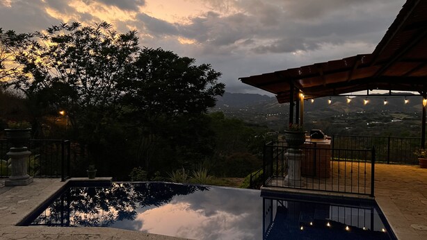 A swimming pool with a view of a mountainous landscape, a pergola with string lights, and a stone pathway. - Endless charm in the heart of the Central Valley (Atenas)