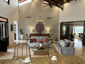 A spacious living room with a high ceiling, a dining area, and a view of the outdoors.