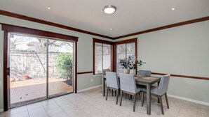 A dining area with a table and chairs, a sliding glass door leading to a patio, and a ceiling with recessed lighting. - The Greenhouse (Houston)