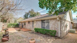 A single-story house with a brick exterior, a front porch, and a small garden area with a potted plant and a stone pathway. - The Greenhouse (Houston)