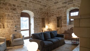 A stone-walled room with a sofa, armchairs, and a table with a lamp. - DONNAPAOLA MODERN FARM (Altamura)