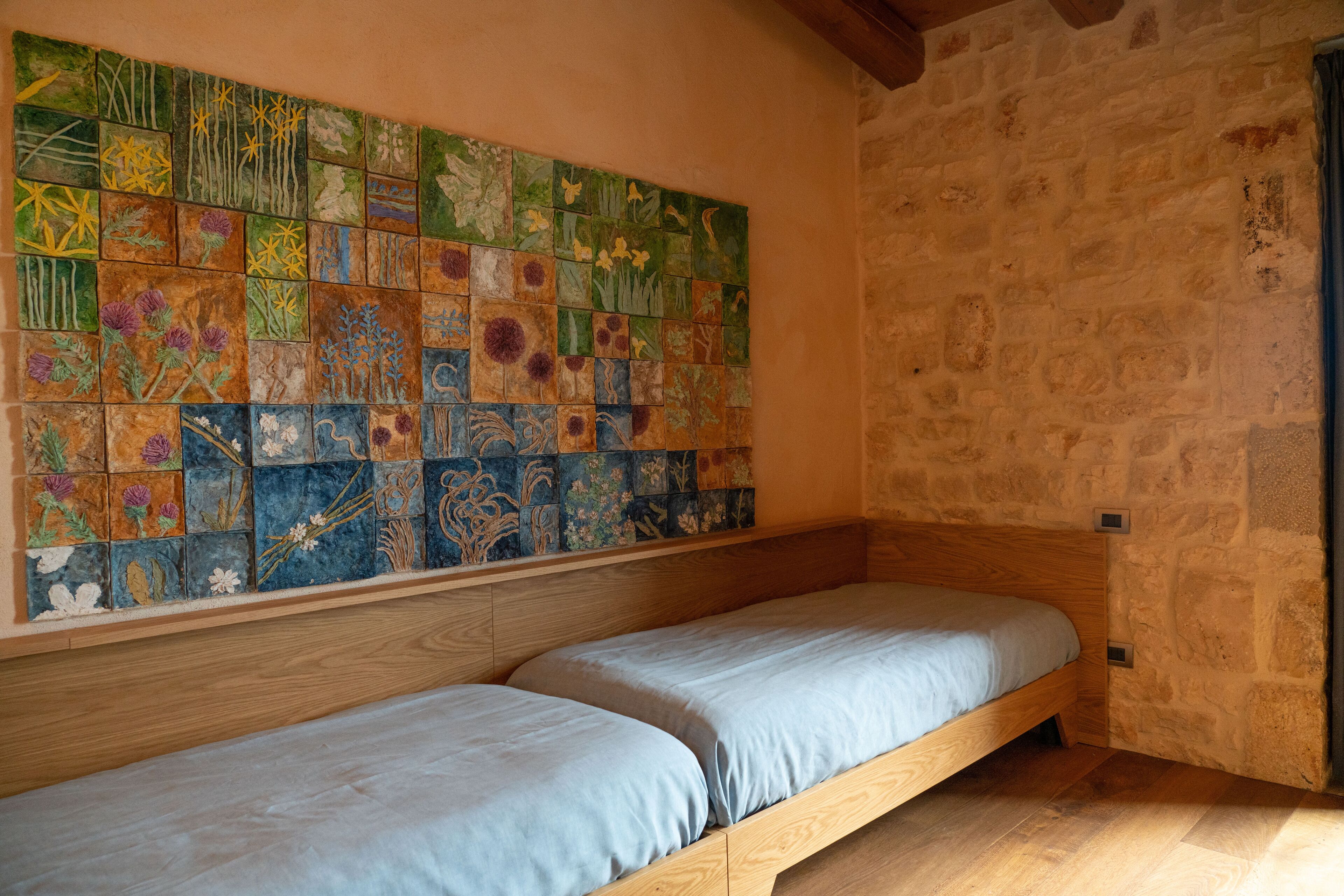 Une pièce avec un lit en bois et un grand mur recouvert de carreaux à motifs floraux.
