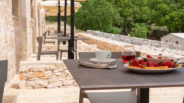 An outdoor café with stone walls, tables, and umbrellas. - DONNAPAOLA MODERN FARM (Altamura)