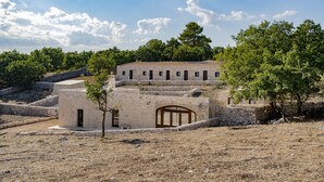 A stone building with a central courtyard, surrounded by trees and a clear sky. - DONNAPAOLA MODERN FARM (Altamura)