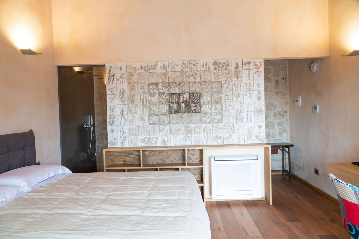 A bedroom with a bed, a desk, and a shower.